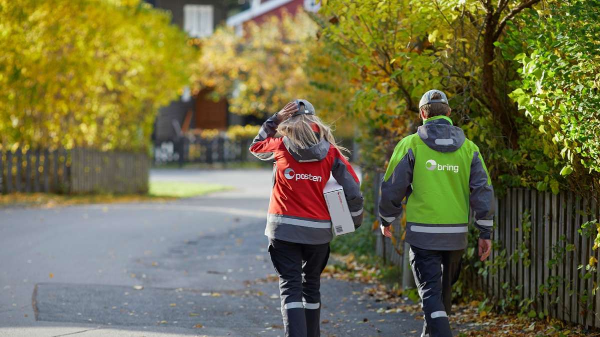 Kvinnelig postbud og mannlig Bring-bud går nedover veien.